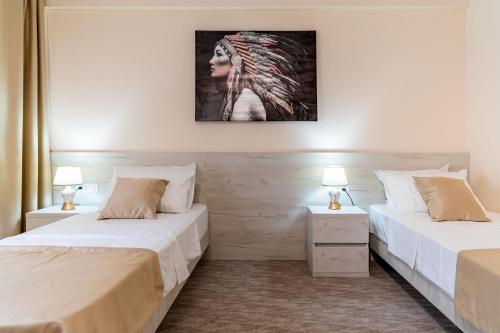 two beds in a room with two lamps at Hotel RIO VERDE in Podgorica