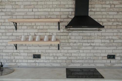 una cucina con parete in mattoni, scaffali e piano cottura di Saliuk Lodge a Solochyn