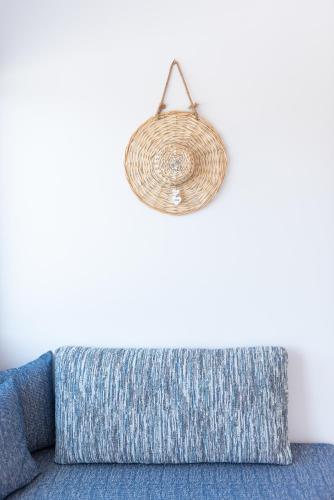 a blue couch with a rattan light hanging over it at Volcanic Arc Suites in Oia