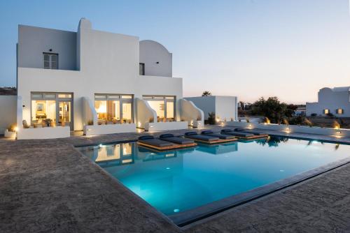 a villa with a swimming pool at night at Volcanic Arc Suites in Oia