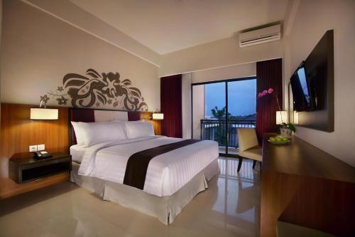 a bedroom with a bed and a balcony with a television at ASTON Bojonegoro City Hotel in Bojonegoro