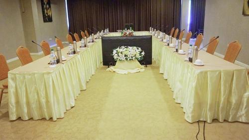 a long row of tables in a room with chairs at Viang Tak Riverside Hotel in Tak