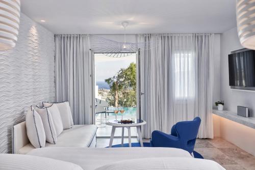 a bedroom with a couch and a table and a window at Myconian Ambassador Relais & Chateaux in Platis Yialos Mykonos