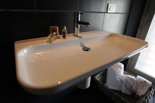 a white sink in a bathroom with a window at Albergo al Vecchio Tram in Udine