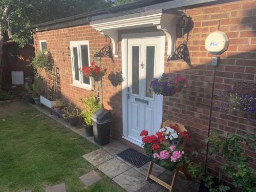 a brick house with a white door and flowers at Studio in Stanmore