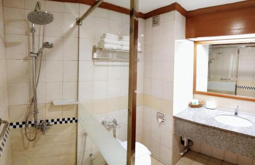 a bathroom with a shower and a sink and a mirror at Viang Tak Riverside Hotel in Tak