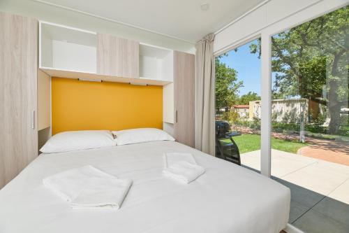 a bedroom with a white bed and a large window at Camping Ulika Mobile Homes - Naturist in Poreč