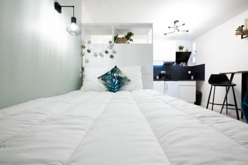 a bedroom with a large white bed with a blue pillow at La Suite Saint Georges - Beau studio cosy et design à 5 mn métro Vieux Lyon in Lyon