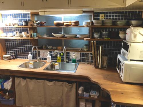 a kitchen with a sink and a microwave at Onomichi Guest House Anago-no-Nedoko in Onomichi