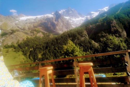 a view of a mountain range with two wooden chairs at Gîte le Rocher - Suitable for people with reduced mobility in La Grave