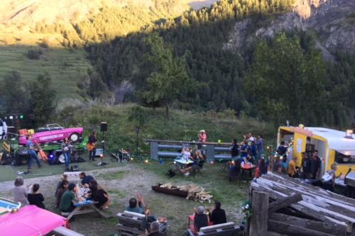 a group of people sitting in the grass next to a trailer at Gîte le Rocher - Suitable for people with reduced mobility in La Grave