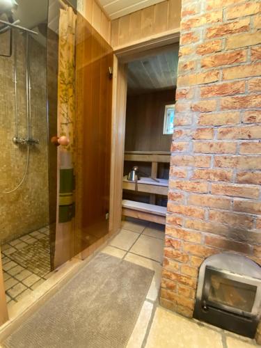 a bathroom with a shower and a brick wall at Villa Hanson in Elbiku