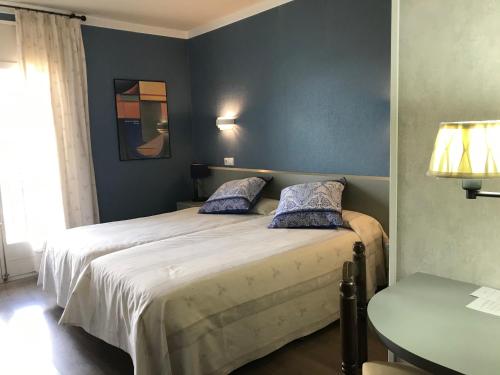 a bedroom with two beds with blue walls and a table at Hotel Esteba in Caldes de Malavella