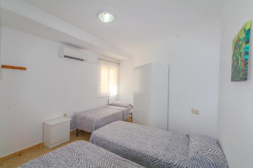 Duas camas num quarto com paredes brancas em Alacant Home: Santa Pola. Piso moderno a 200 metros de la playa em Santa Pola