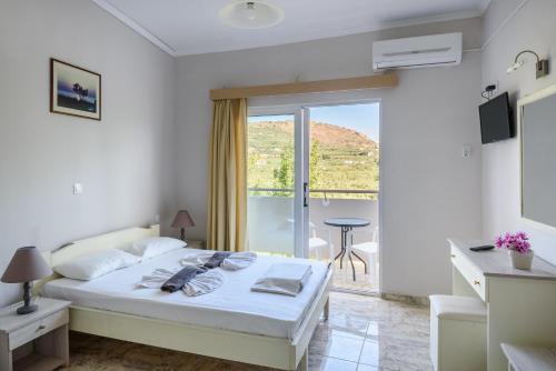 a white bedroom with a bed and a balcony at Regina Hotel in Kissamos