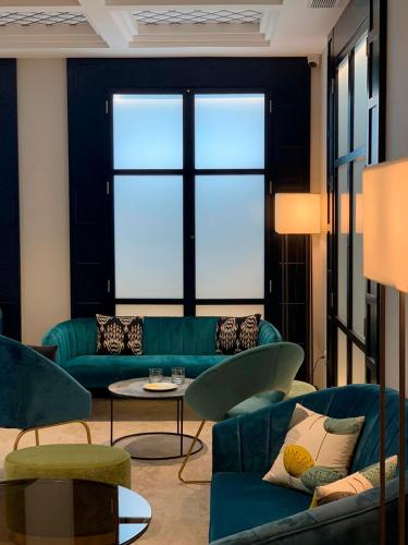 a living room with blue couches and a large window at Abba San Sebastián Hotel in Donostia-San Sebastián