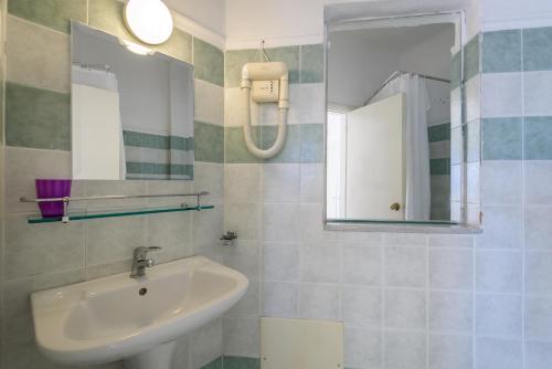 ein Bad mit einem Waschbecken und einem Spiegel in der Unterkunft Regina Hotel in Kissamos