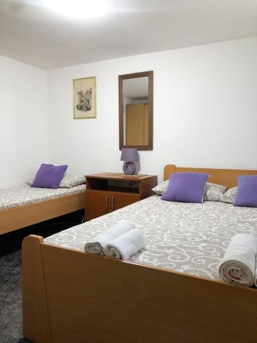 a bedroom with two beds with purple pillows and a mirror at Apartments Moracanin in Sutomore