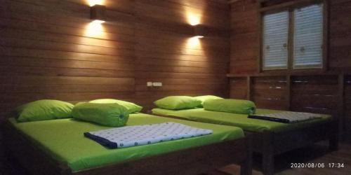 - 2 lits dans une chambre avec des draps et des oreillers verts dans l'établissement NAYYLA Homestay, à Pangandaran