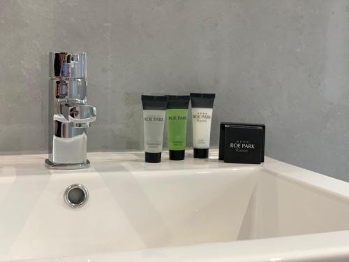 un lavandino bianco del bagno con due bottiglie di crema idratante di Roe Park Resort a Limavady