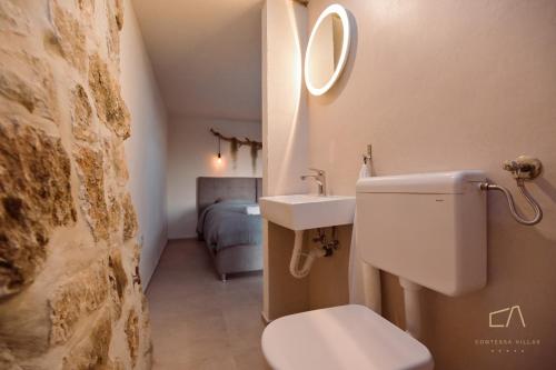 a bathroom with a toilet and a sink and a bed at Heritage Stonehouse Jure in Krk