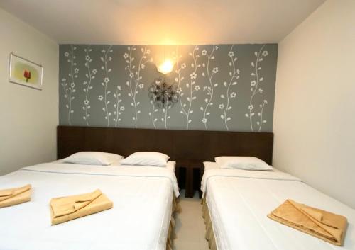 two twin beds in a room with a wall at Phang Nga Guesthouse in Phangnga