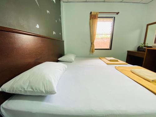 a bedroom with a large white bed and a window at Phang Nga Guesthouse in Phangnga