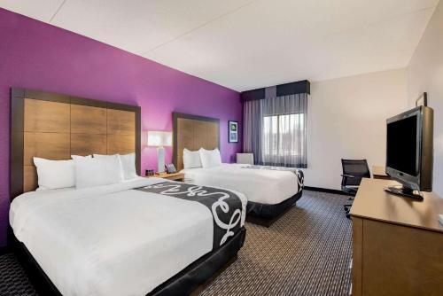 a hotel room with two beds and a flat screen tv at La Quinta by Wyndham Baltimore BWI Airport in Linthicum Heights