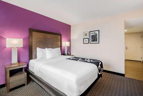 a large bed in a hotel room with purple walls at La Quinta by Wyndham Baltimore BWI Airport in Linthicum Heights