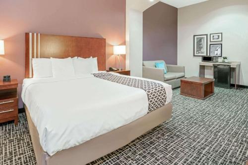a hotel room with a large bed and a chair at La Quinta by Wyndham Oklahoma City -Yukon in Yukon