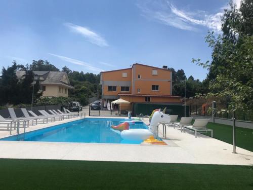 a swimming pool with a inflatable dolphin in a yard at Pensión CHE in O Pedrouzo