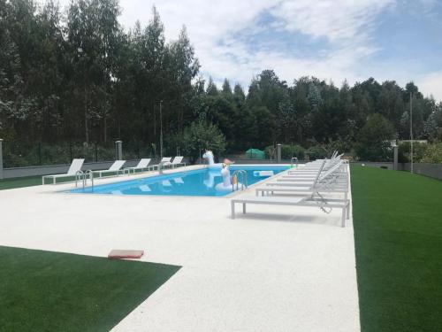 a swimming pool with benches in a park at Pensión CHE in O Pedrouzo