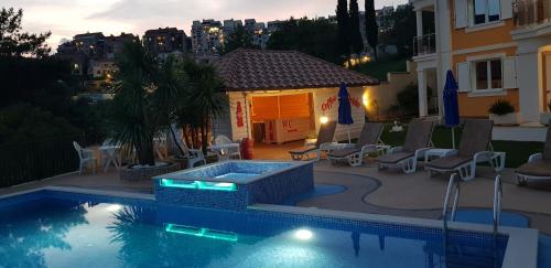 a swimming pool with chairs and a house at Apartmani Niksic in Herceg-Novi