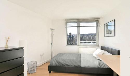 a white bedroom with a bed and a window at Perfectly Located Beautiful Ensuite and Gym in London