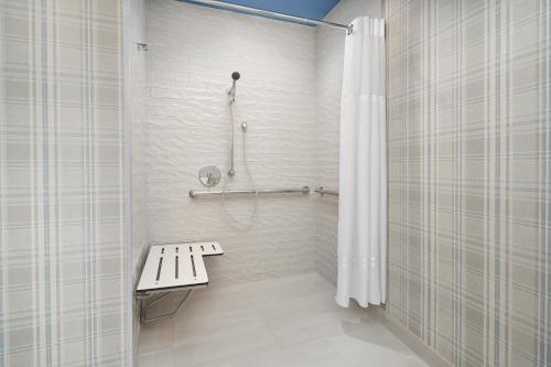 baño con ducha con banco y cortina de ducha en Hotel Indigo Tallahassee - Collegetown, an IHG Hotel, en Tallahassee