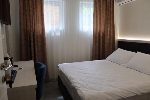 een slaapkamer met een bed, een tafel en een raam bij DM Sobe in Tuzla