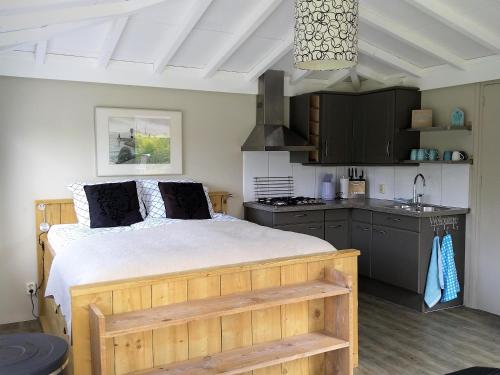 a bedroom with a large bed and a kitchen at Tuinverblijf Lauwersmeer in Anjum