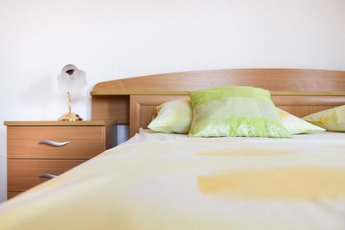 1 cama con cabecero de madera y almohada verde en Apartments Marušić, en Vinišće
