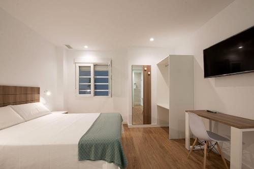 a bedroom with a bed and a desk and a television at Hostal Beach in Santa Pola