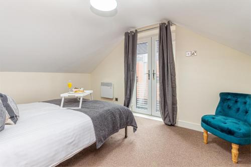 um quarto com uma cama e uma cadeira azul em Guest Homes - Carriage Court em Worcester