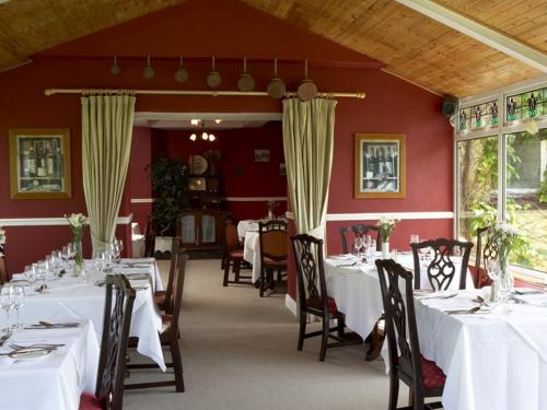een eetkamer met witte tafels en stoelen bij Carrygerry Country House in Shannon