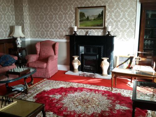 a living room with a fireplace and a pink chair at Carrygerry Country House in Shannon