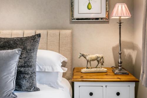 a nightstand with a horse statue on it next to a bed at The Lodge @ Carus Green in Kendal