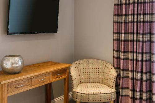 una silla junto a un escritorio con TV en The Lodge @ Carus Green en Kendal