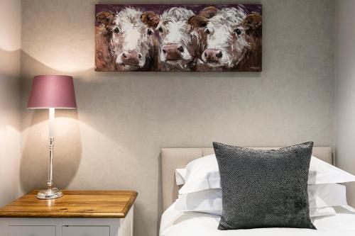 a bedroom with a painting of cows on the wall at The Lodge @ Carus Green in Kendal