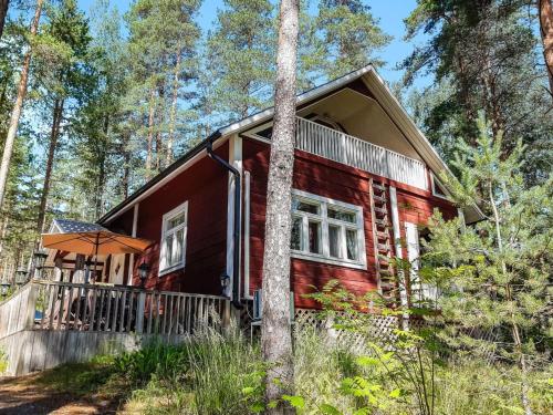 une cabane rouge dans les bois avec un parapluie dans l'établissement Holiday Home Piilutupa by Interhome, à Luhanka
