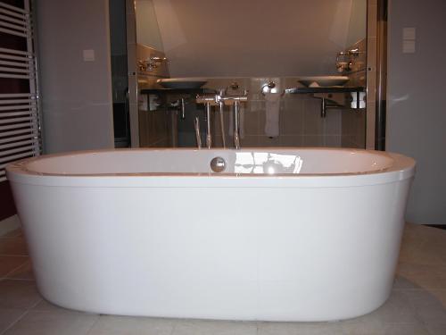 a white tub in a bathroom with a sink at Chambres d'hôtes Au Clos de Beaulieu in Bossée