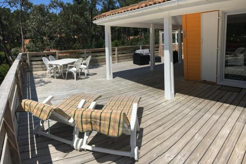 a wooden deck with chairs and a table on it at Chalet orange naturiste la Jenny in Le Porge