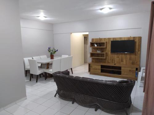 een woonkamer met een televisie en een tafel en stoelen bij Apartamento na Praia da Enseada in Guarujá