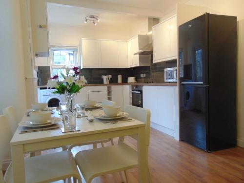 a kitchen with a table with chairs and a black refrigerator at Ceres Lodge in Plumstead